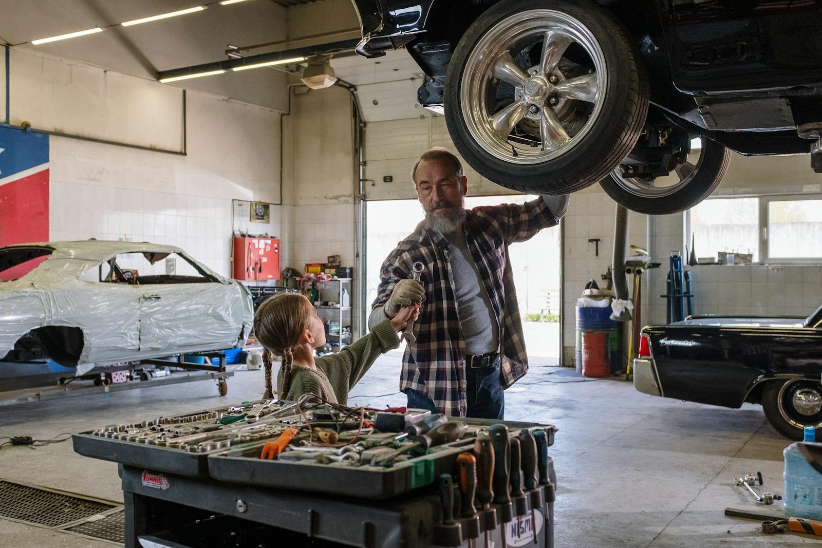 Father and daughter bonding while repairing a car in an auto workshop, symbolizing family togetherness.